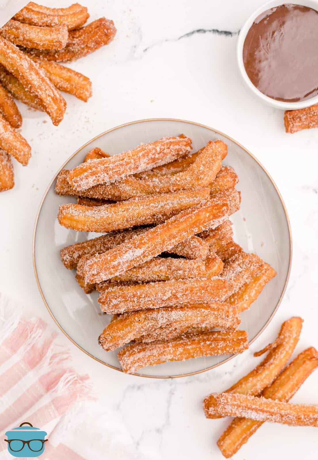 Overhead of stacked Homemade Churros on white plate.