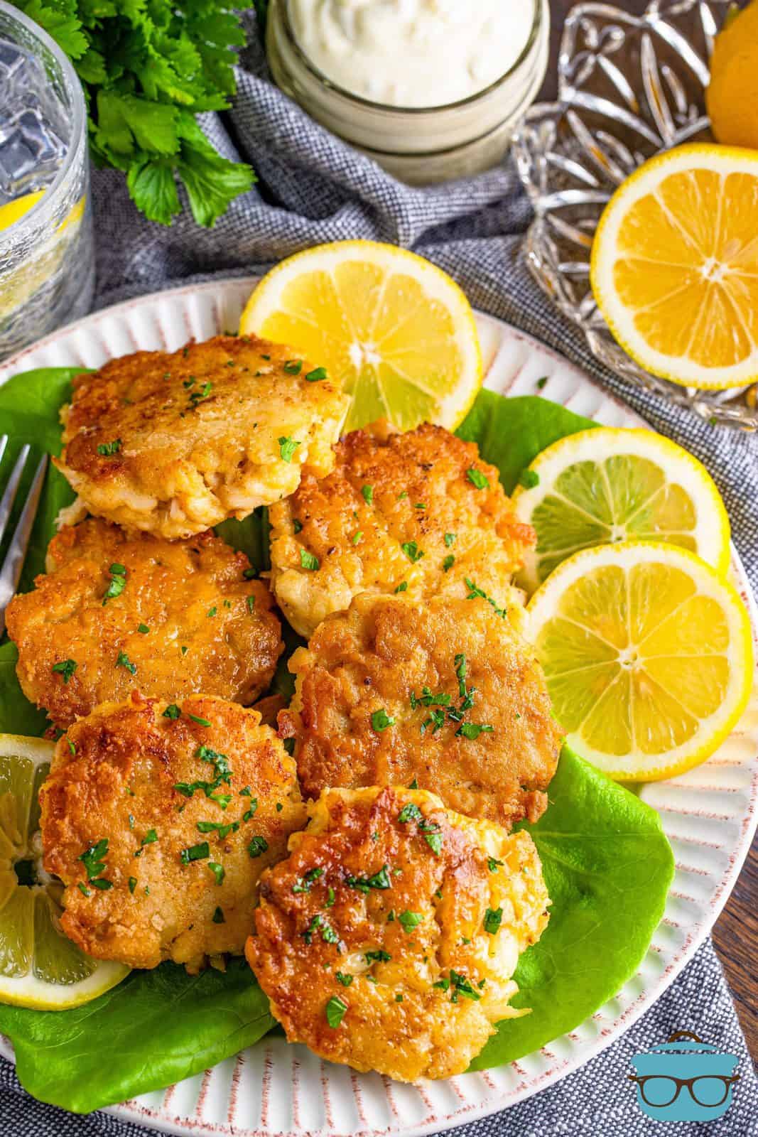 Overhead of stacked Southern Crab Cakes on plate with lettuce and lemon slices.