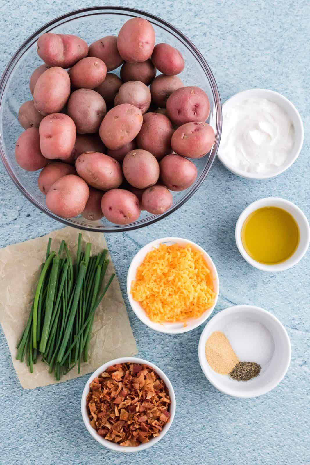 Ingredients needed: baby potatoes, olive oil, salt, garlic powder, pepper, cheddar cheese, sour cream, bacon crumbles and chives.