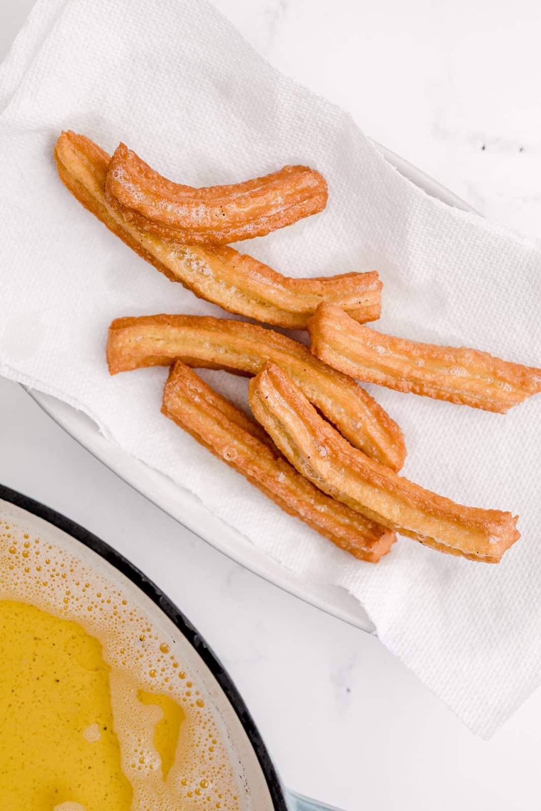Churros removed to quickly drain on paper towels.