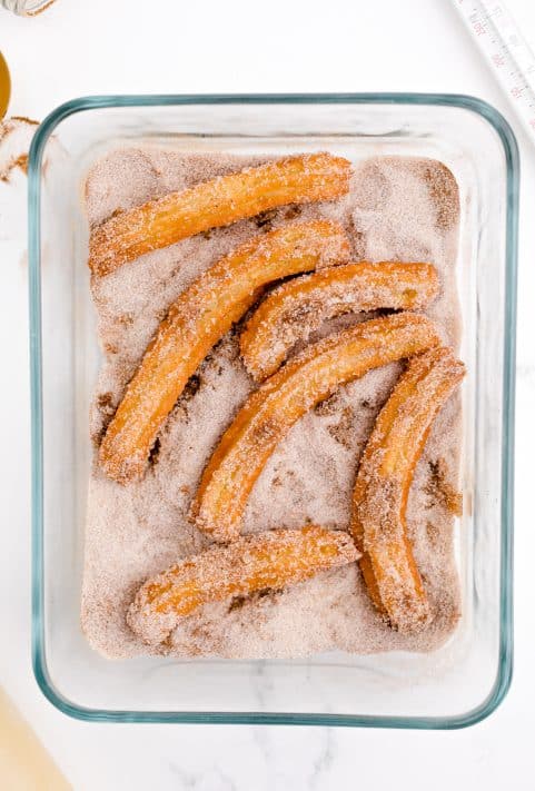 Churros being tossed in the cinnamon sugar mixture.