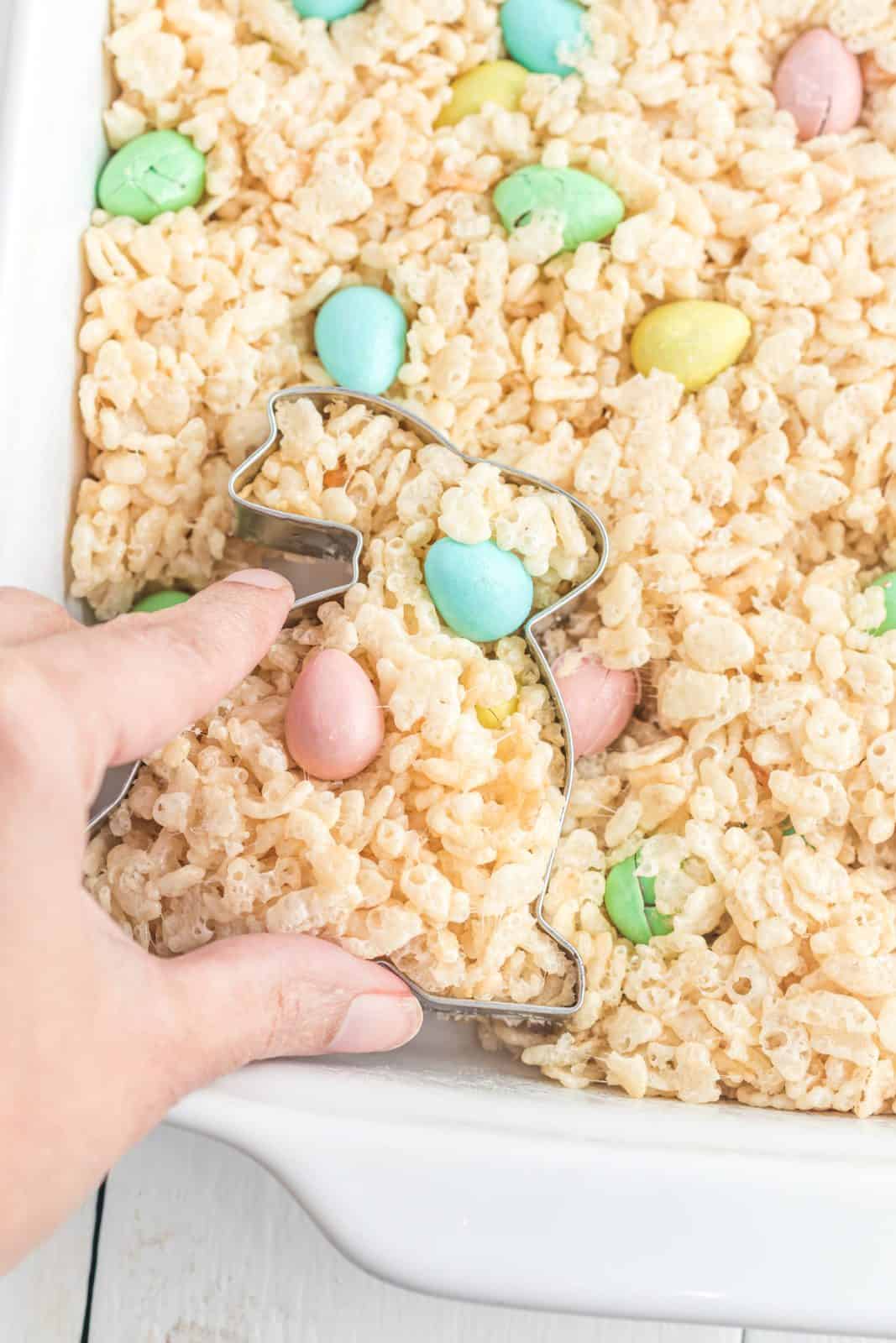 Hand cutting out bunny shapes out of finished Rice Krispies Treats.