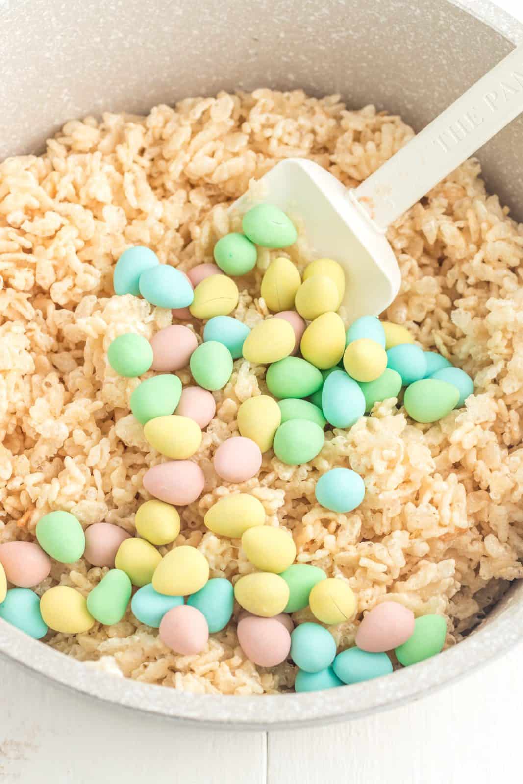 Cadbury mini eggs and Rice Krispies being stirred into the marshmallow mixture.