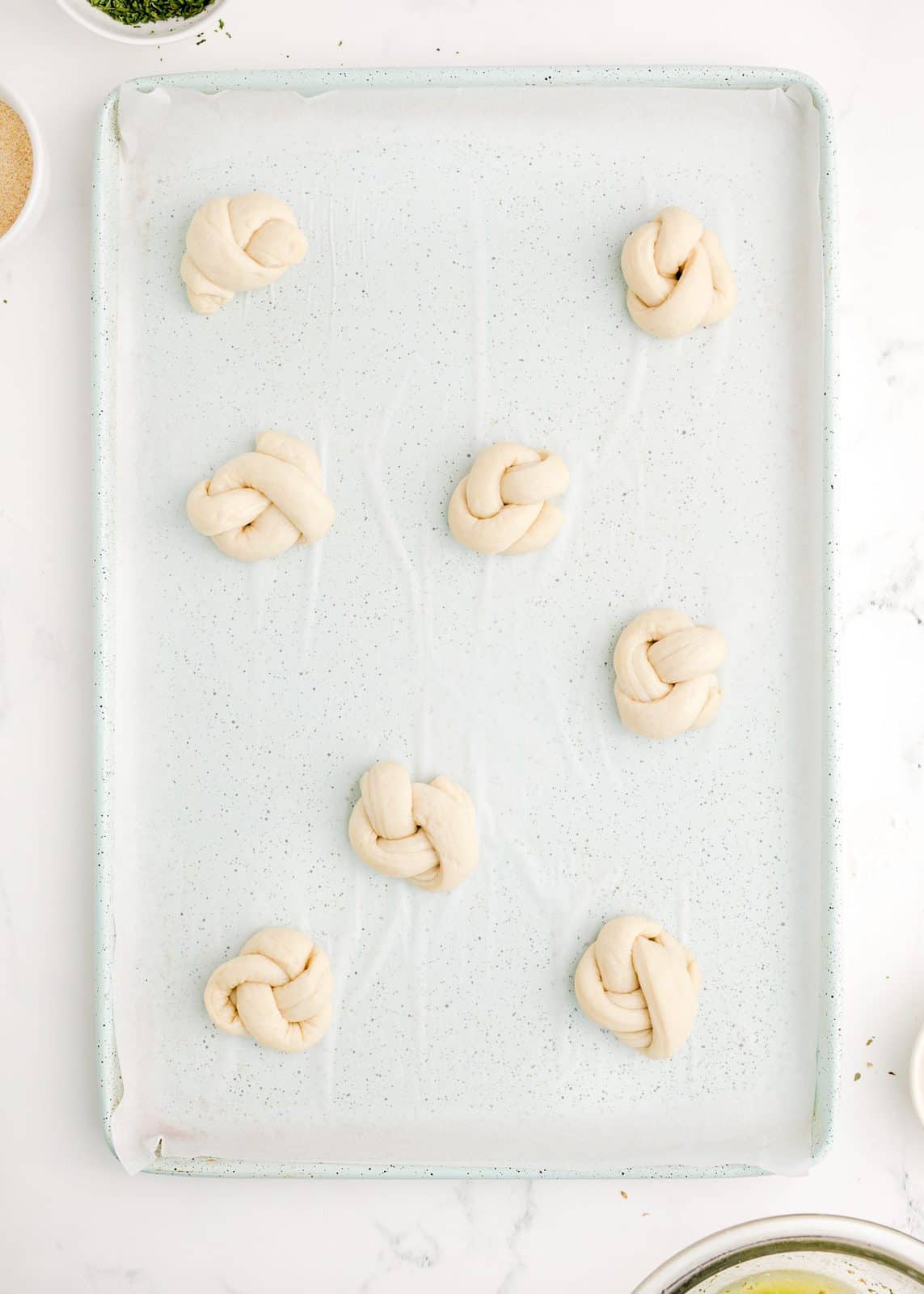 Garlic knots placed on parchment line baking sheet.