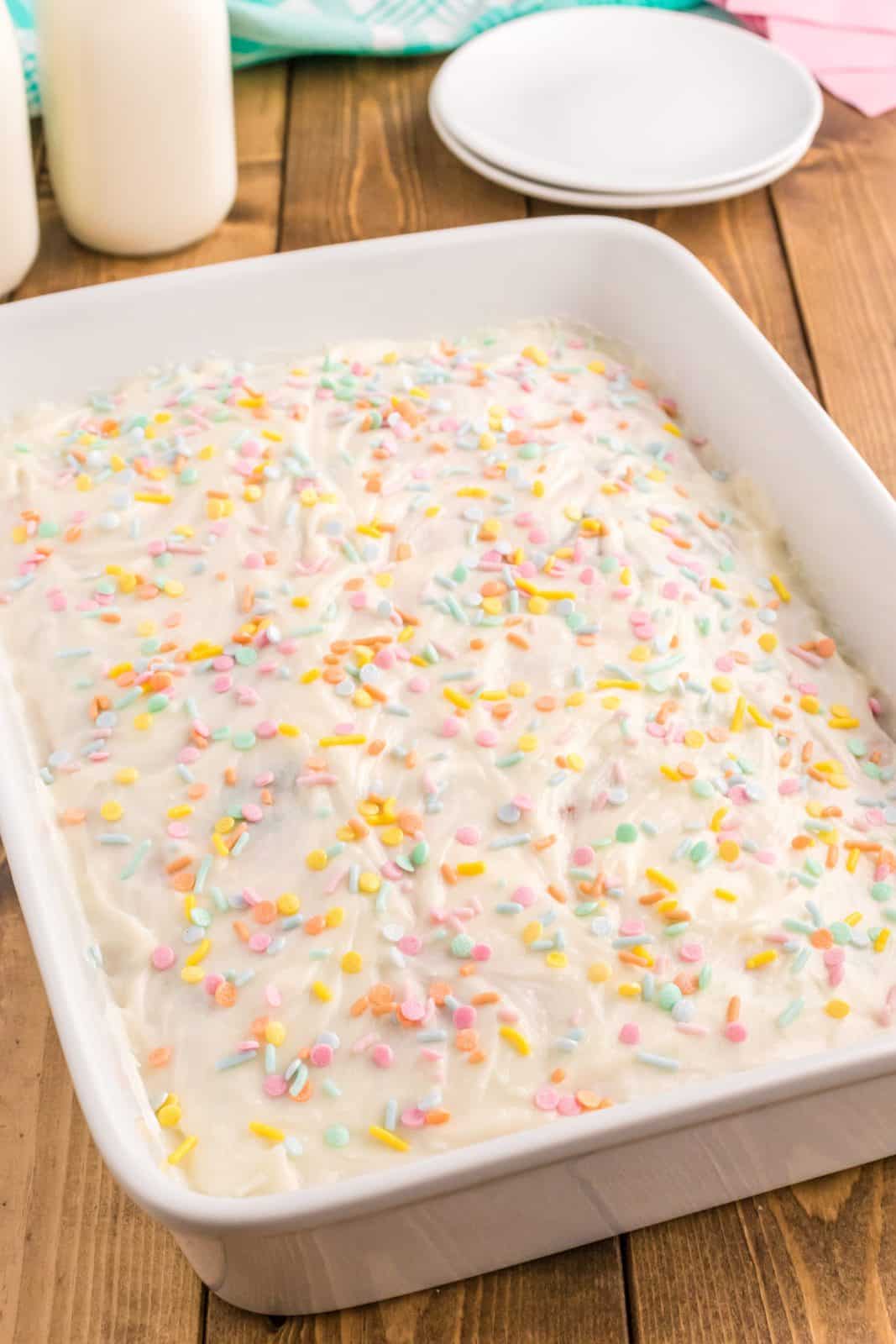 Sprinkles added to frosted cake.