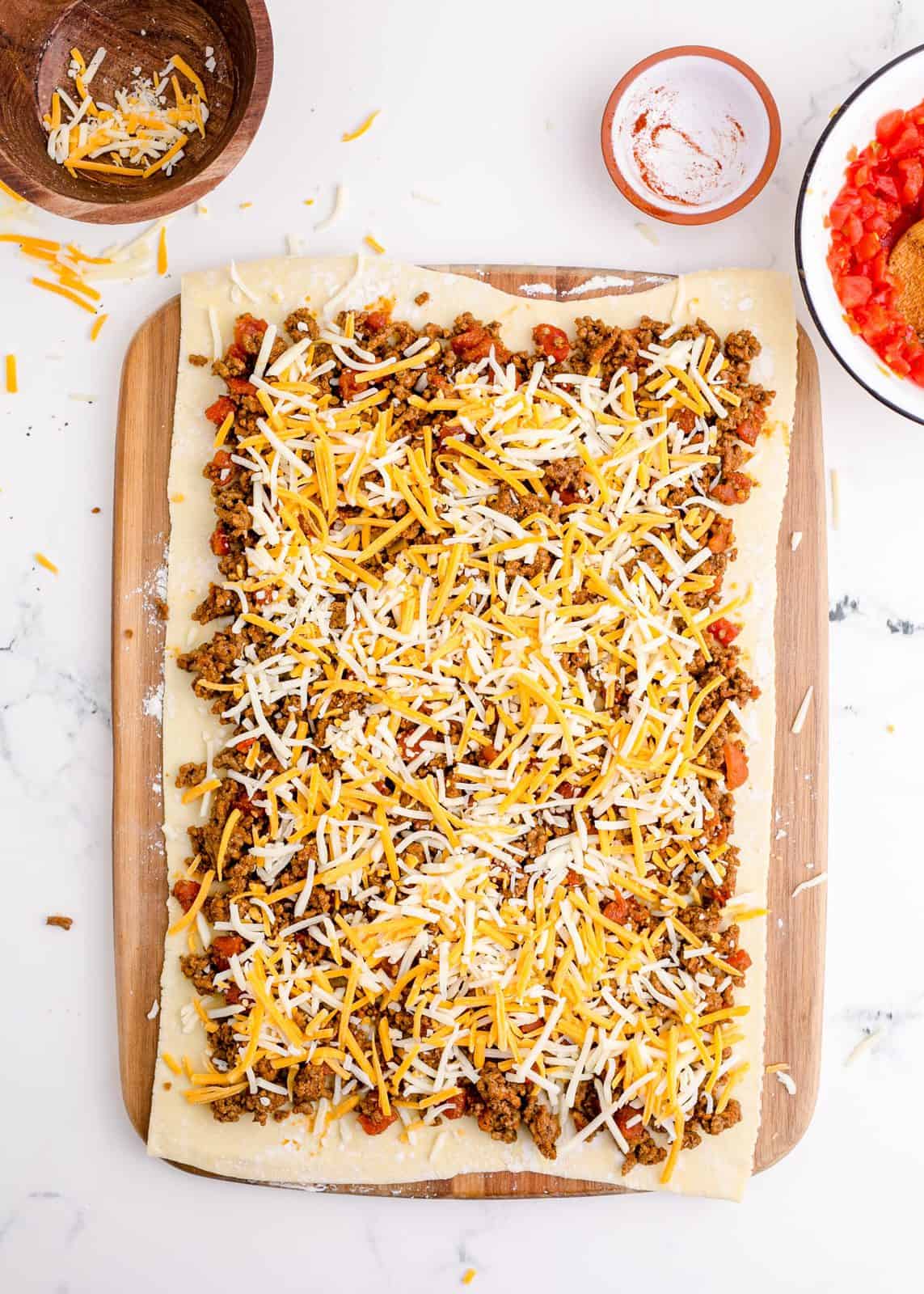 Taco mixture and cheese spread over puff pastry.