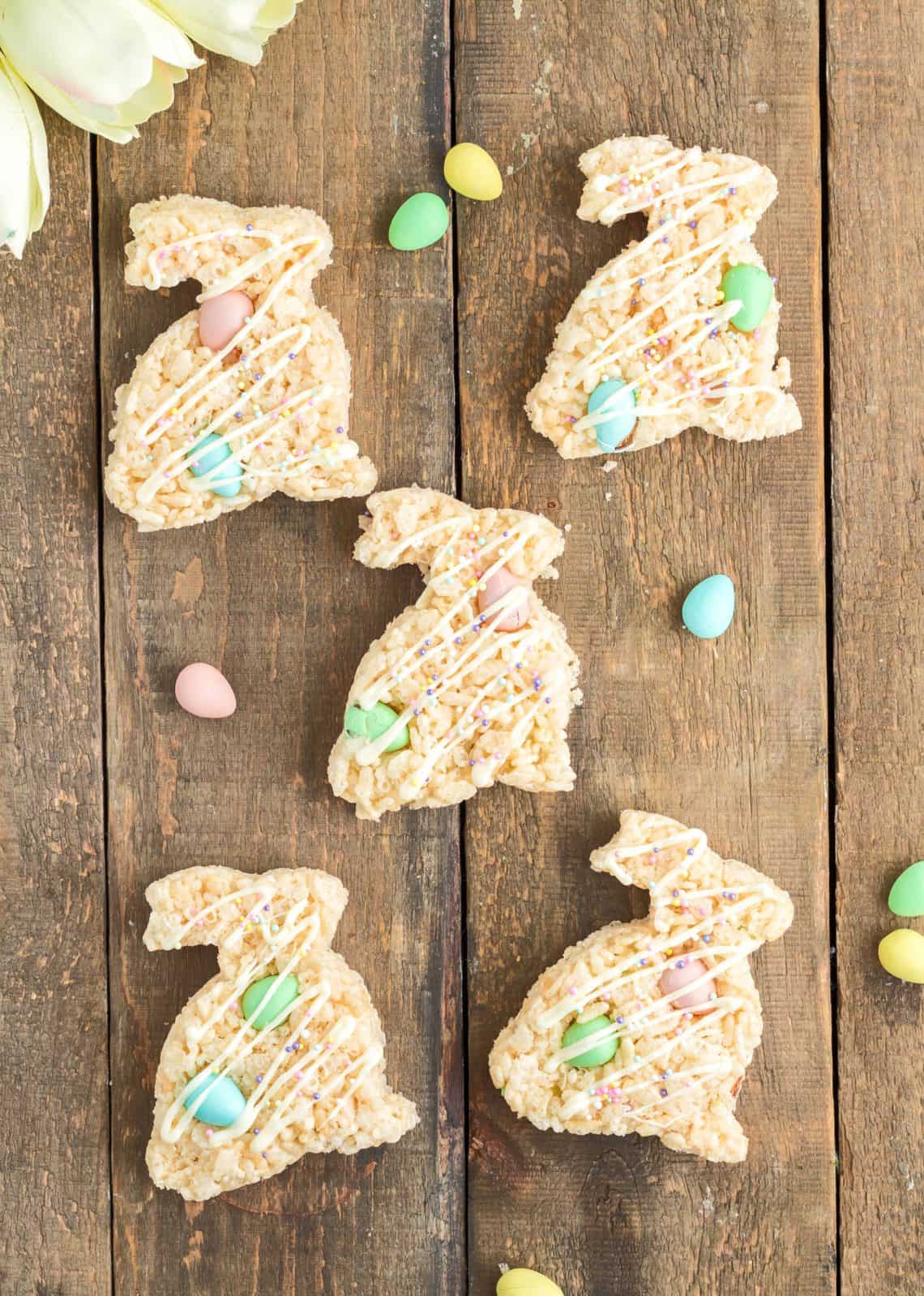 Easter Bunny Rice Krispies Treats laying out on wooden board with some mini cadbury eggs.