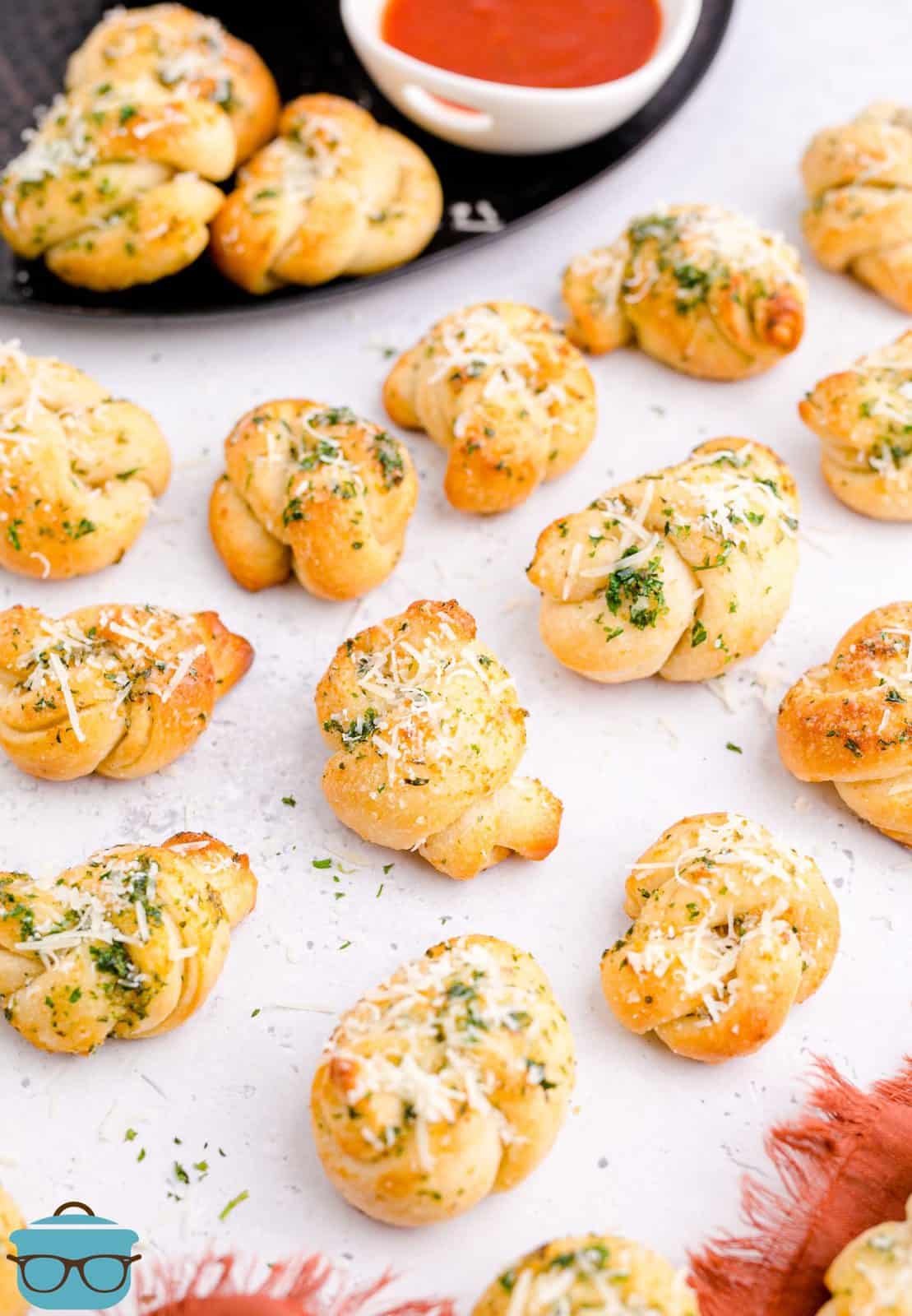Finished Easy Garlic Knots on white board sprinkled with cheese.