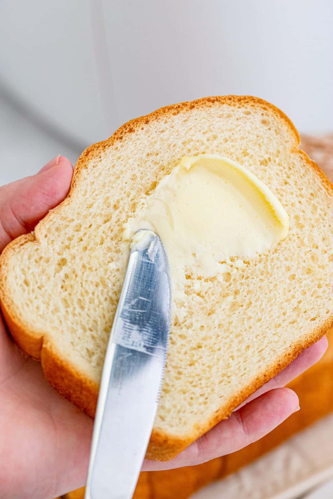Butter being put on one slice of bread.