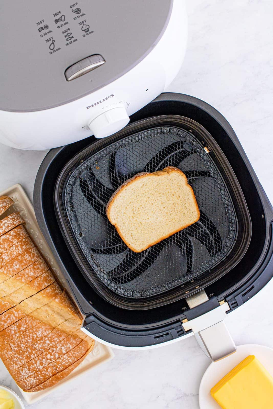 Buttered bread placed buttered side down in air fryer basket.