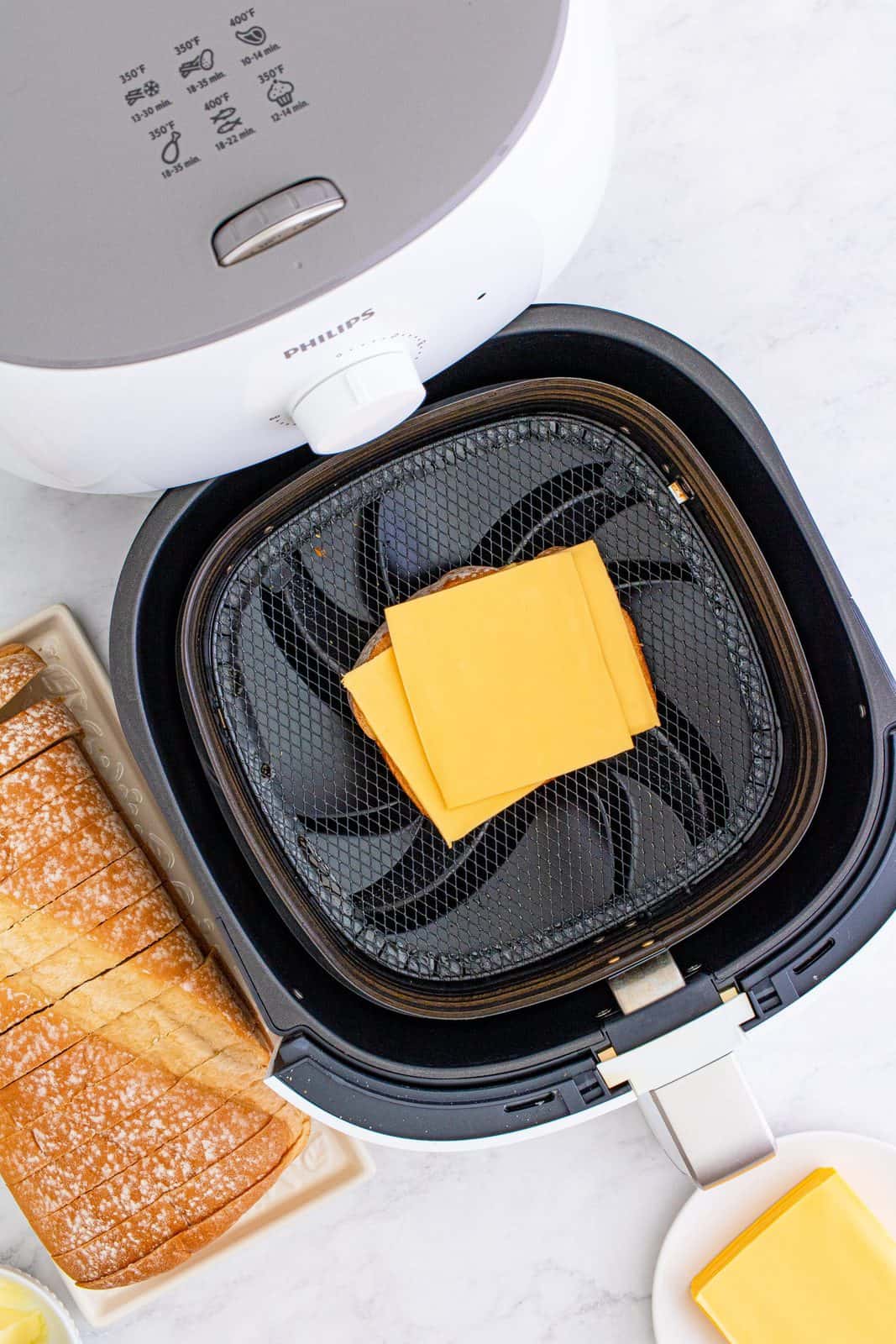 Cheese added to top of bread in air fryer basket.