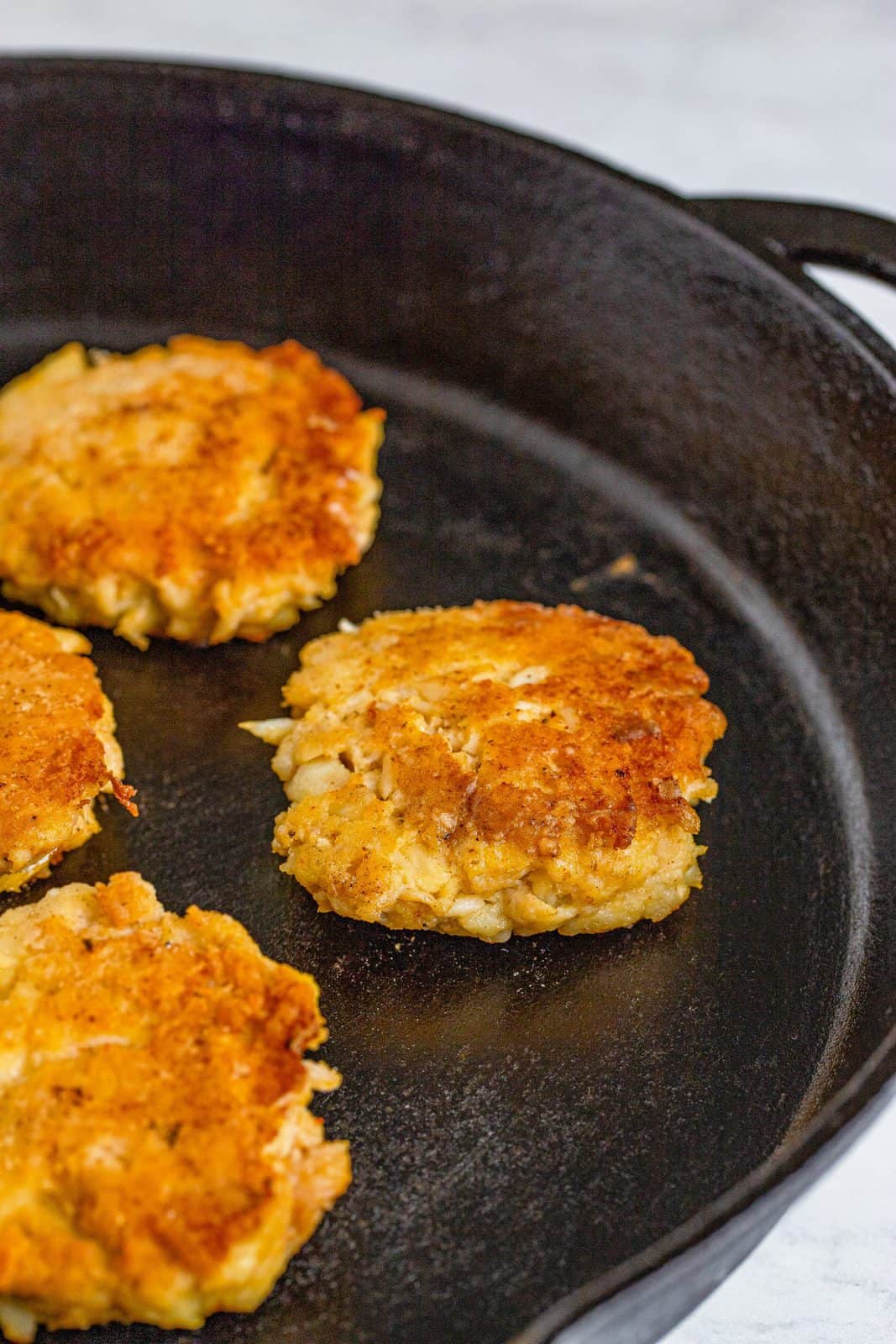 Crab Cakes being browned in a skillet.