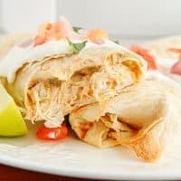 Square image of finished Air Fryer Chicken Chimichangas topped and split and half.