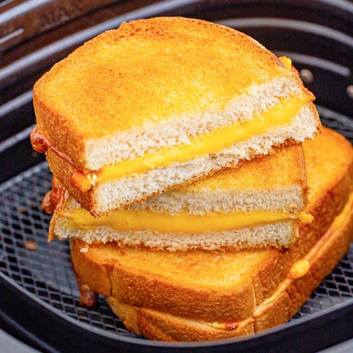One whole and one cut Air Fryer Grilled Cheese square image in air fryer basket.