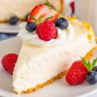Immagine quadrata ravvicinata di una cheesecake senza cottura condita con panna montata e frutta.
