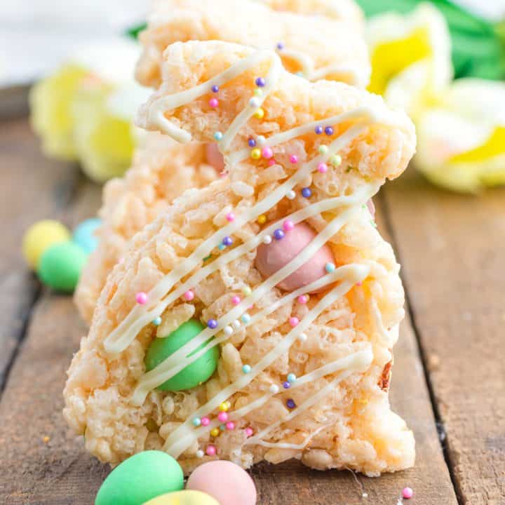 Square image of Easter Bunny Rice Krispies Treats standing up on wooden board with mini cadbury eggs.