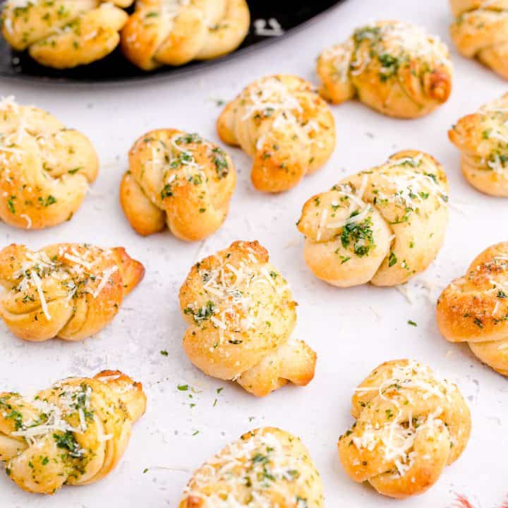 Finished Easy Garlic Knots on white top topped with cheese square image.