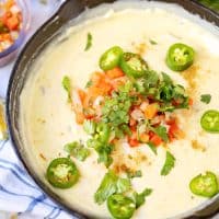 Close up square image of Skillet White Queso Dip with garnishes on top.
