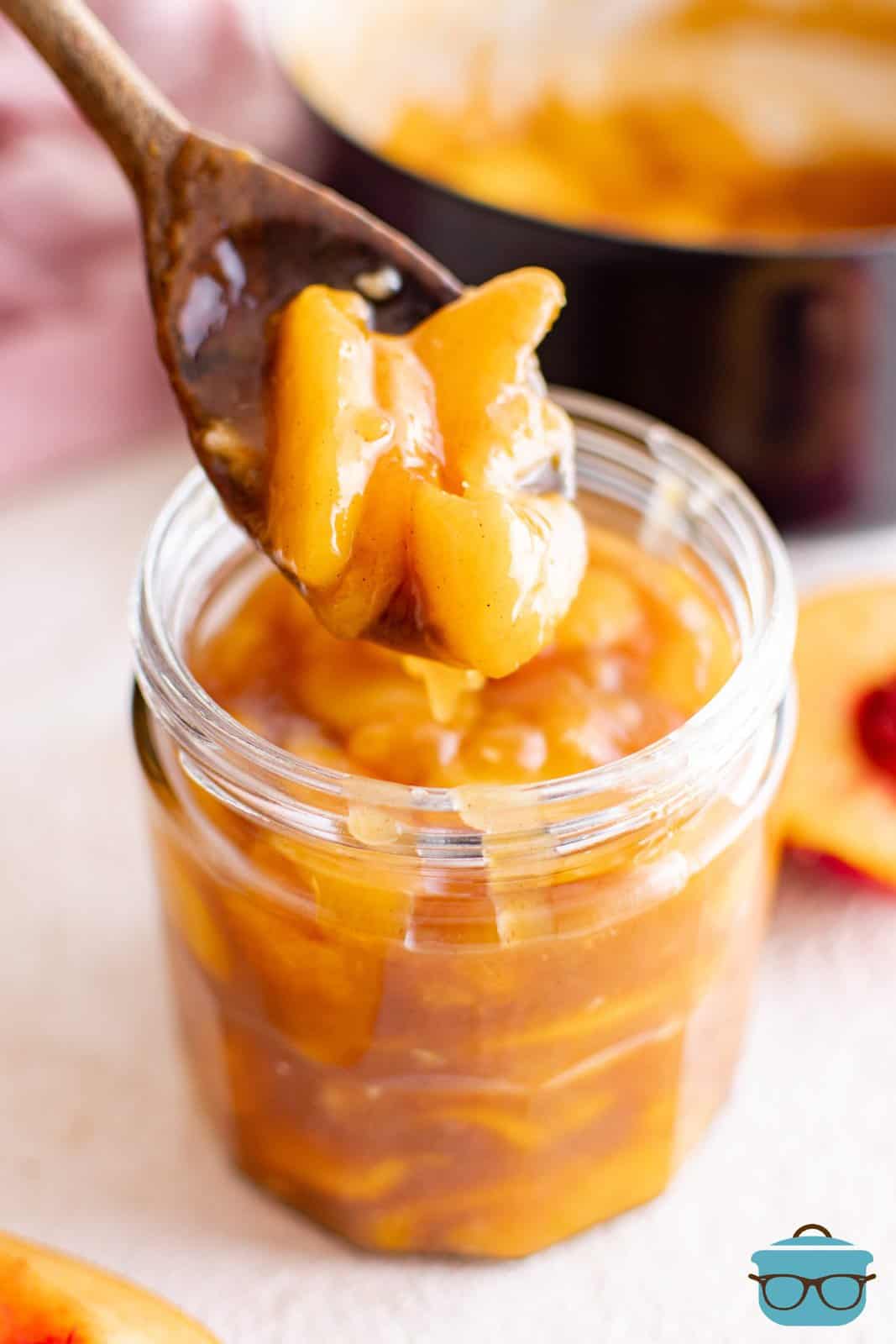 Homemade Peach Pie filling in mason jar with spoon holding some filling out.