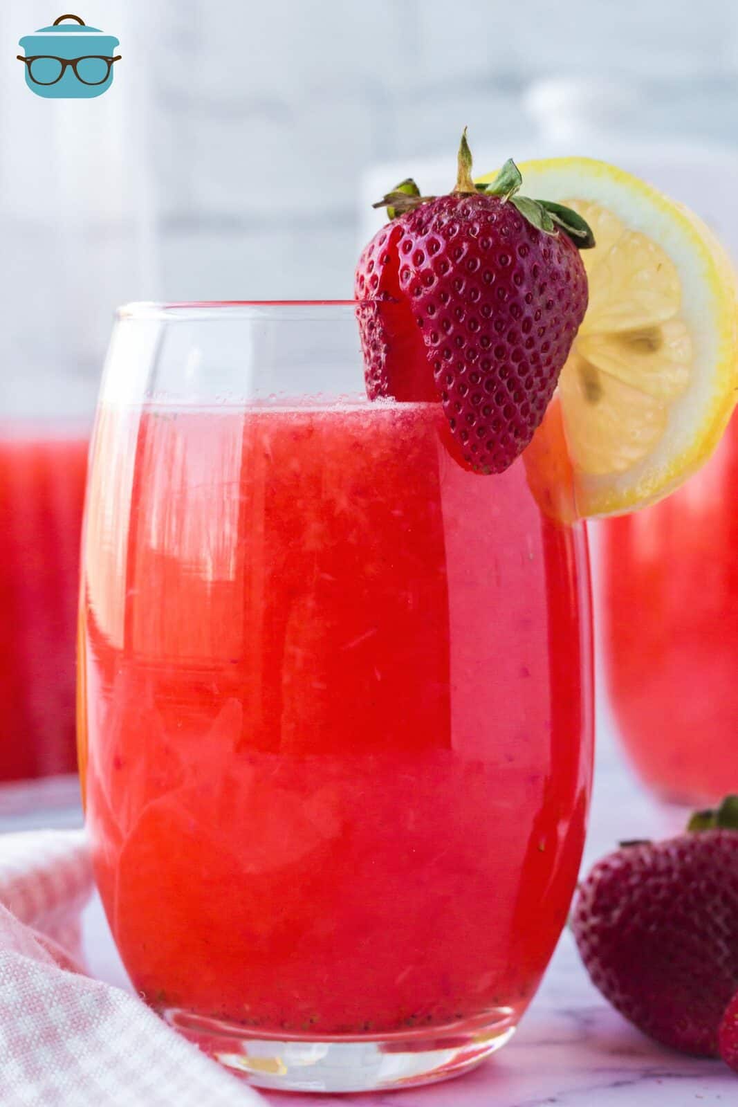 Strawberry Lemonade in glass garnished with strawberry and lemon slice.