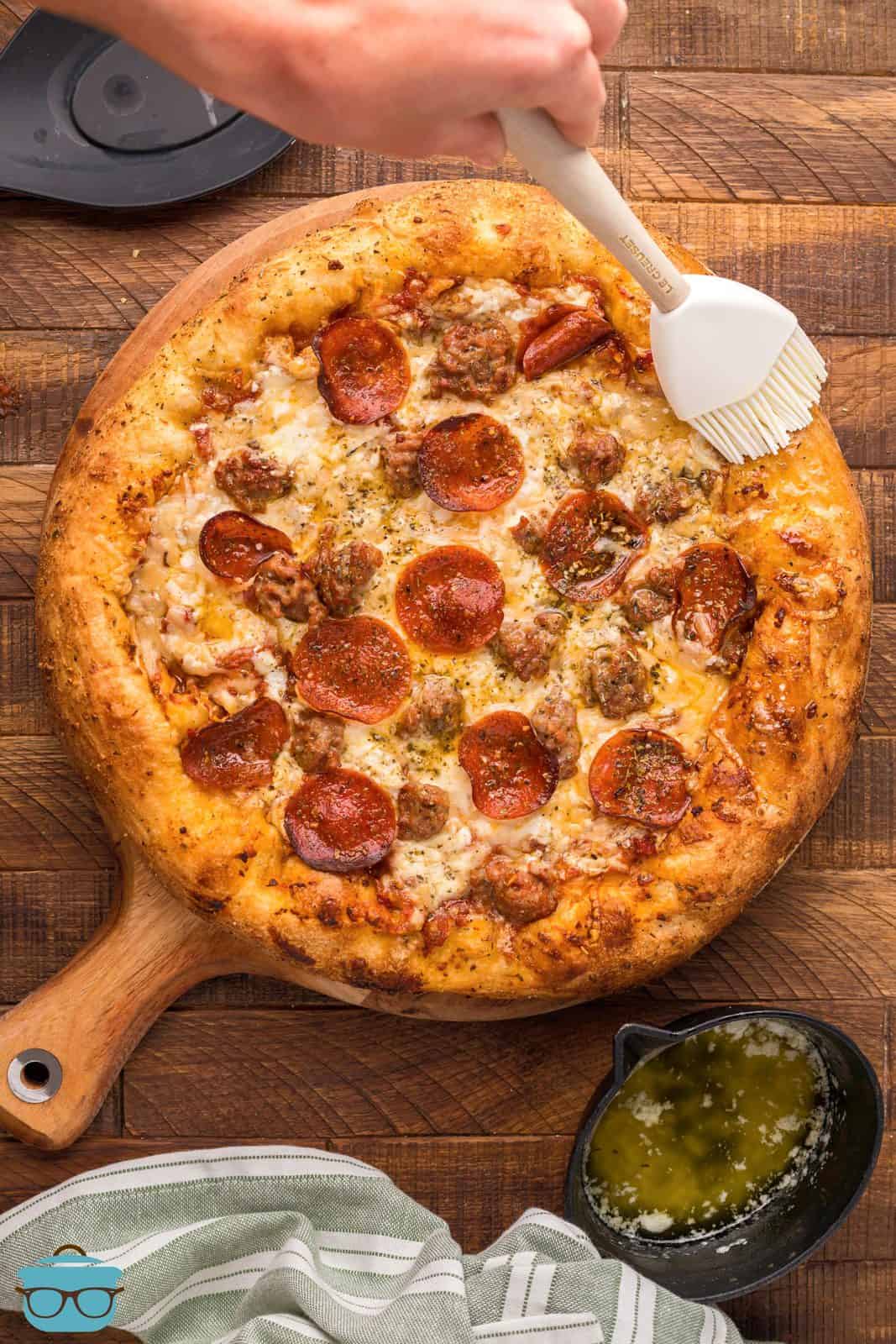 Spennellare a mano la miscela di burro intorno alla crosta della pizza ai peperoni affumicati.