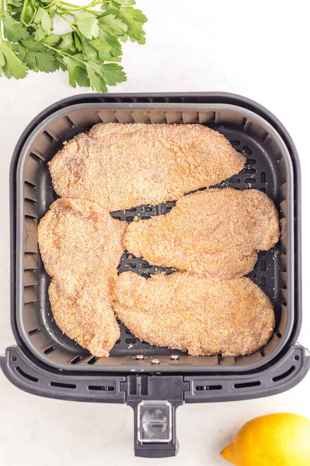 Cutlets placed into basket of air fryer.