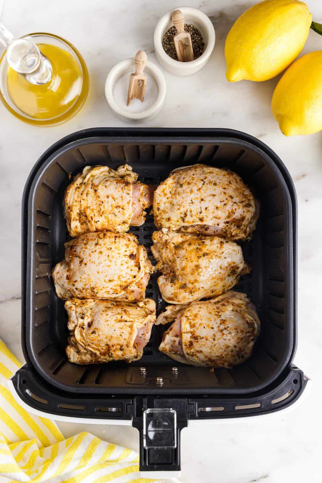 Chicken thighs placed into air fryer basket.