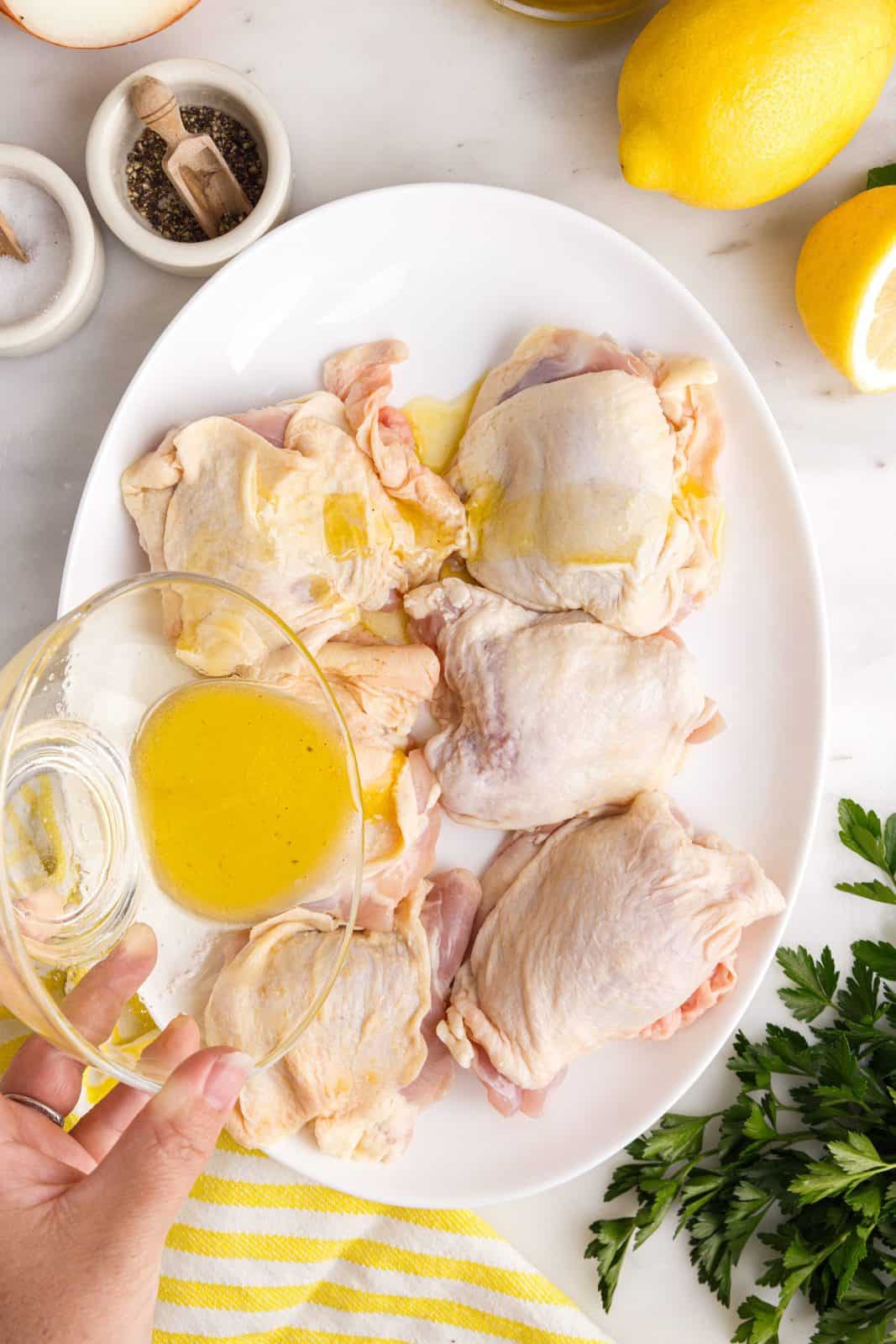 La miscela di olio e succo di limone viene versata sulle cosce di pollo.