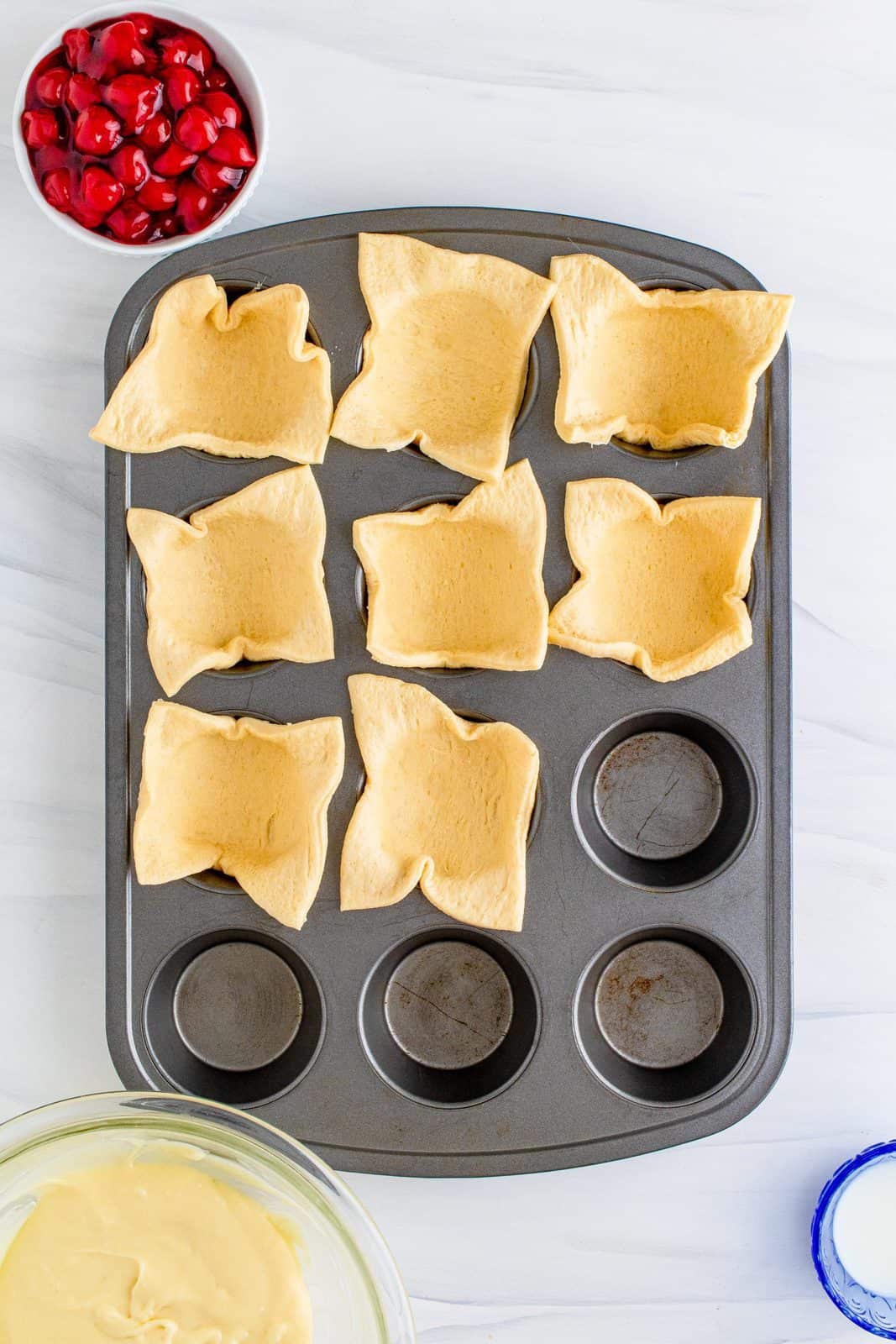 Tagliare l'impasto a mezzaluna pressato nei pozzetti di uno stampo per muffin.