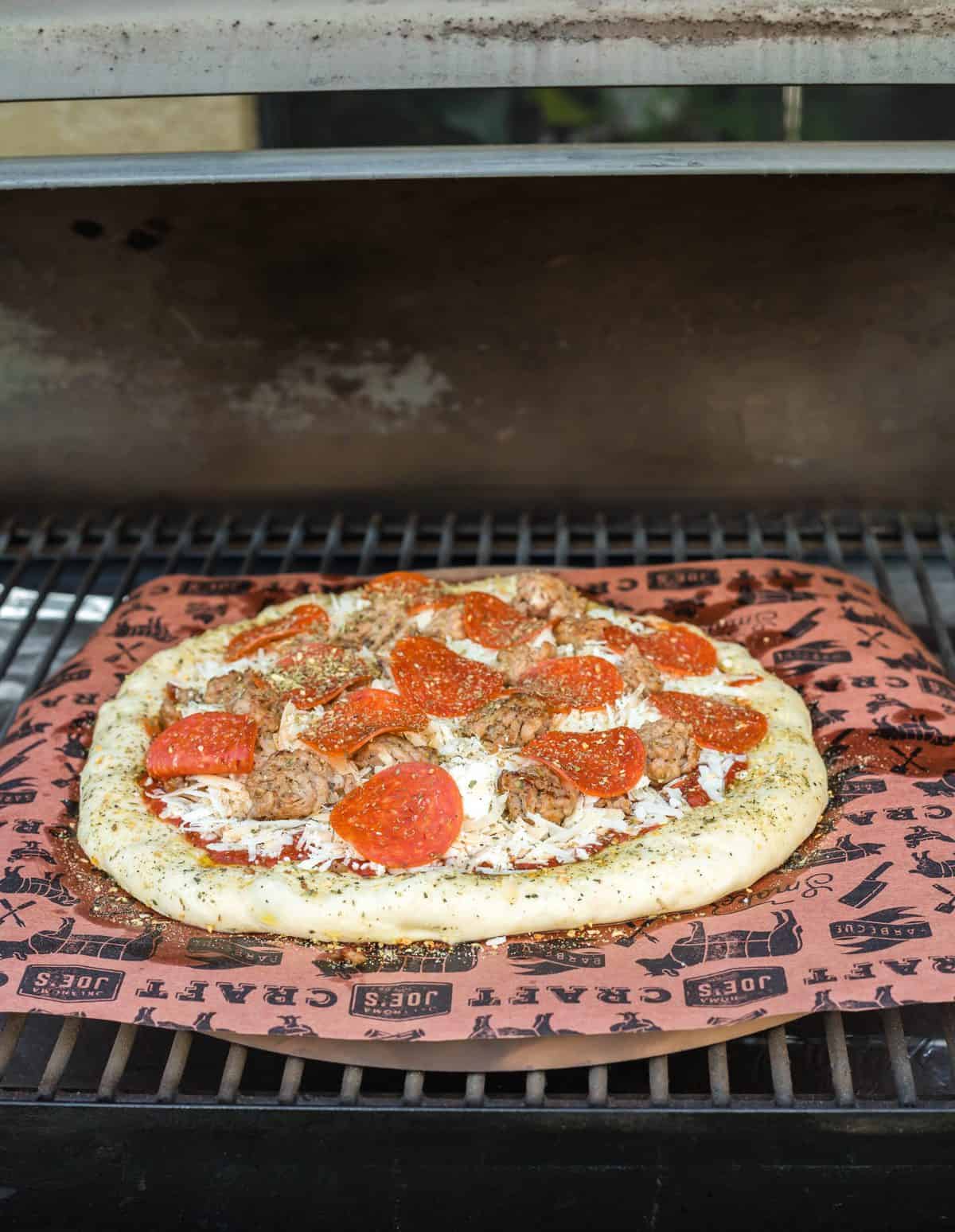 Pizza on parchment paper added to smoker.