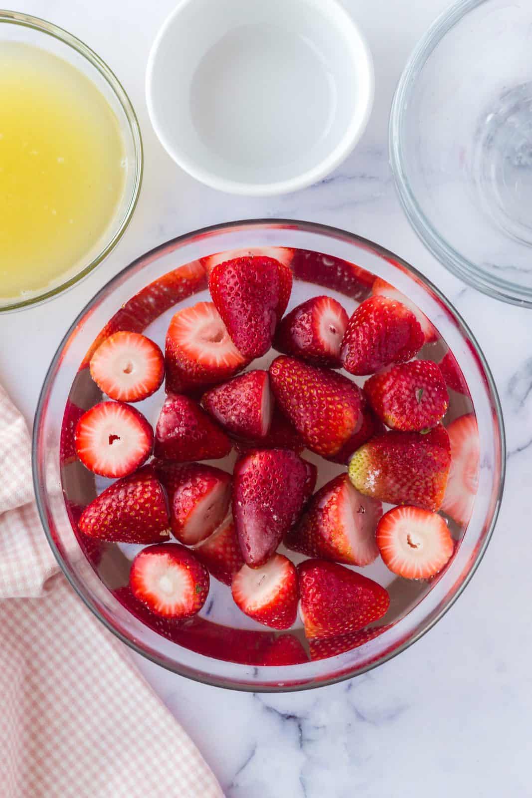 Water, sugar and strawberries in bowl.