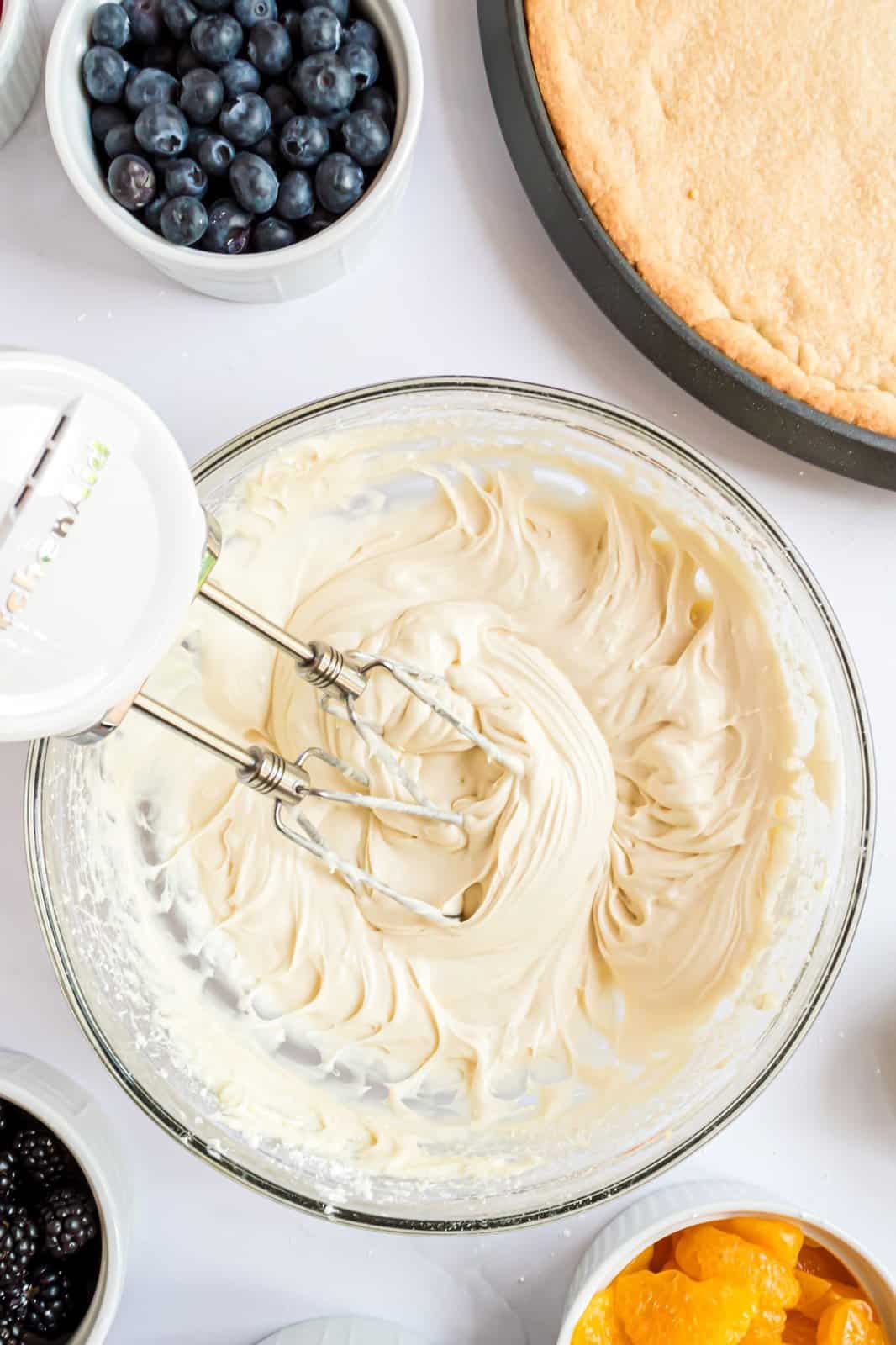 Zucchero a velo e vaniglia sbattuti nella miscela di crema di formaggio in una ciotola.