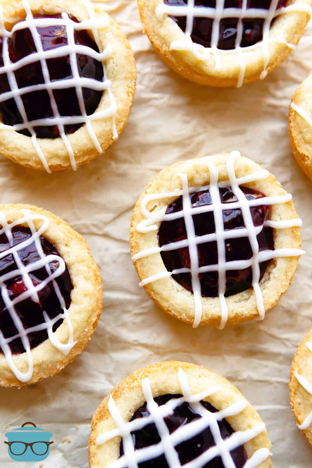 Overhead of Berry Cookie Cups on parchment paper drizzled with glaze.