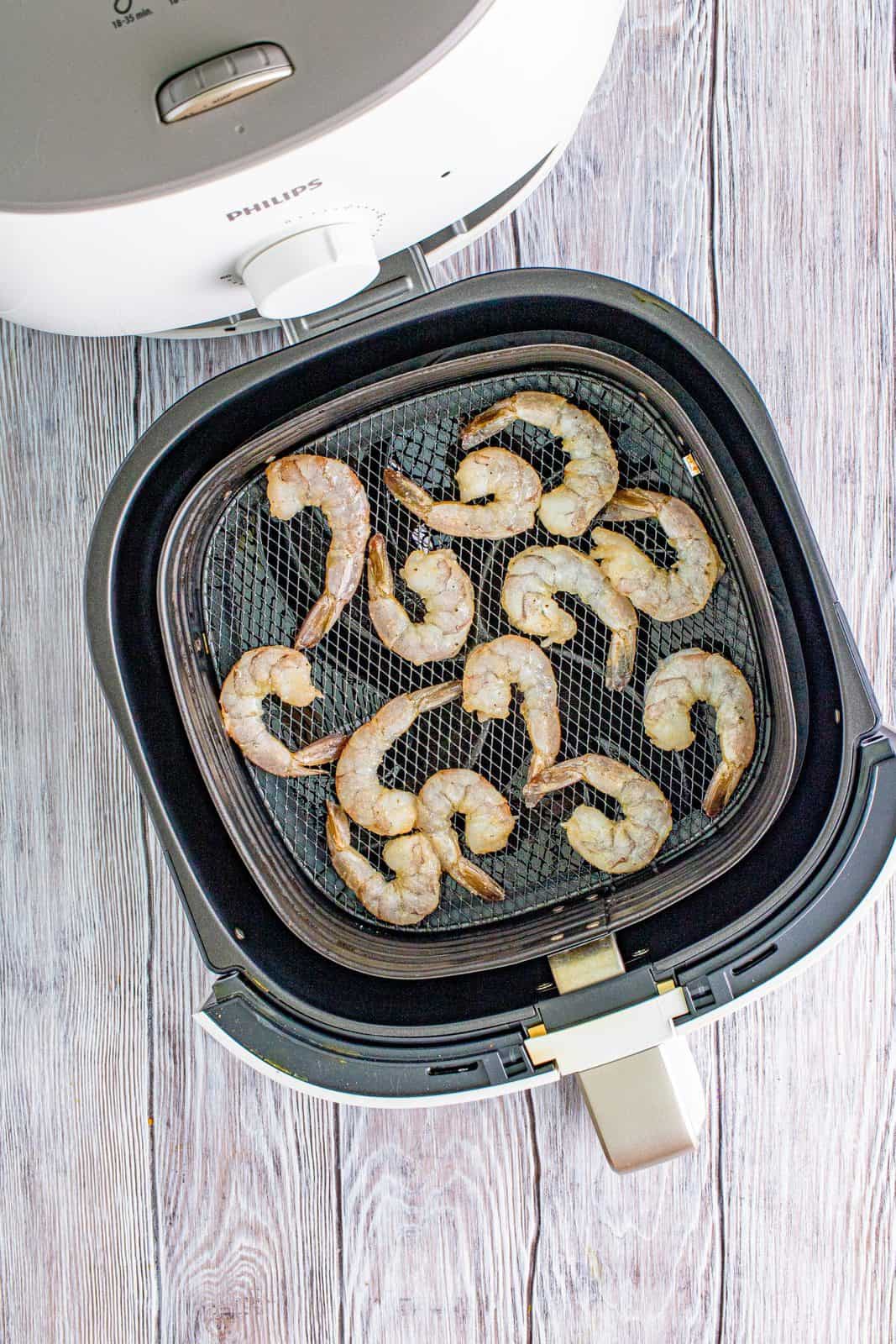 Seasoned shrimp placed into prepared air fryer basket.