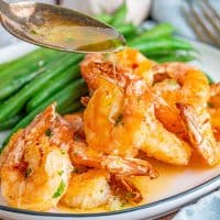 Square image of Air Fryer Garlic Butter Shrimp close up with spoon drizzling butter over shrimp.