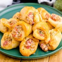 Square image of Air Fryer Sausage and Cream Cheese Crescents stacked on green plate.