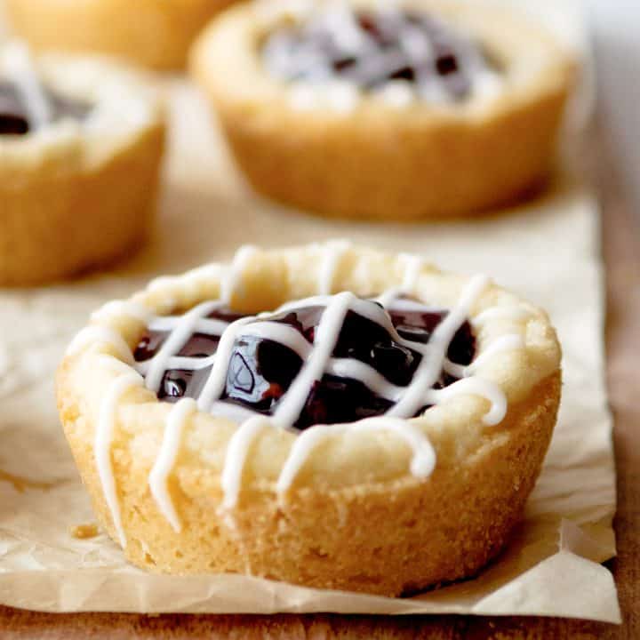 Square image close up of Berry Cookie Cups on parchment with glaze.