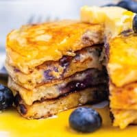 Square image of stacked Blueberry Pancakes with triangle cut removed.