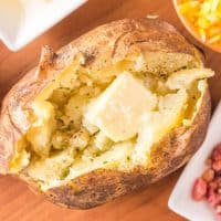 Square image of Grilled Baked Potatoes overhead with butter pat/