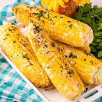 Square image of stacked Grilled Corn on white platter.