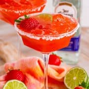 Square image of a Strawberry Margarita close up showing salt rim and garnishes.