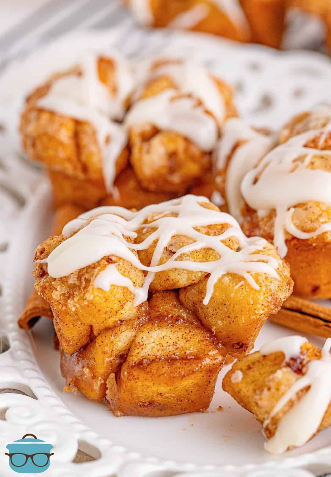 Cinnamon Roll Monkey Bread Muffins on white platter with glaze drizzled over top.