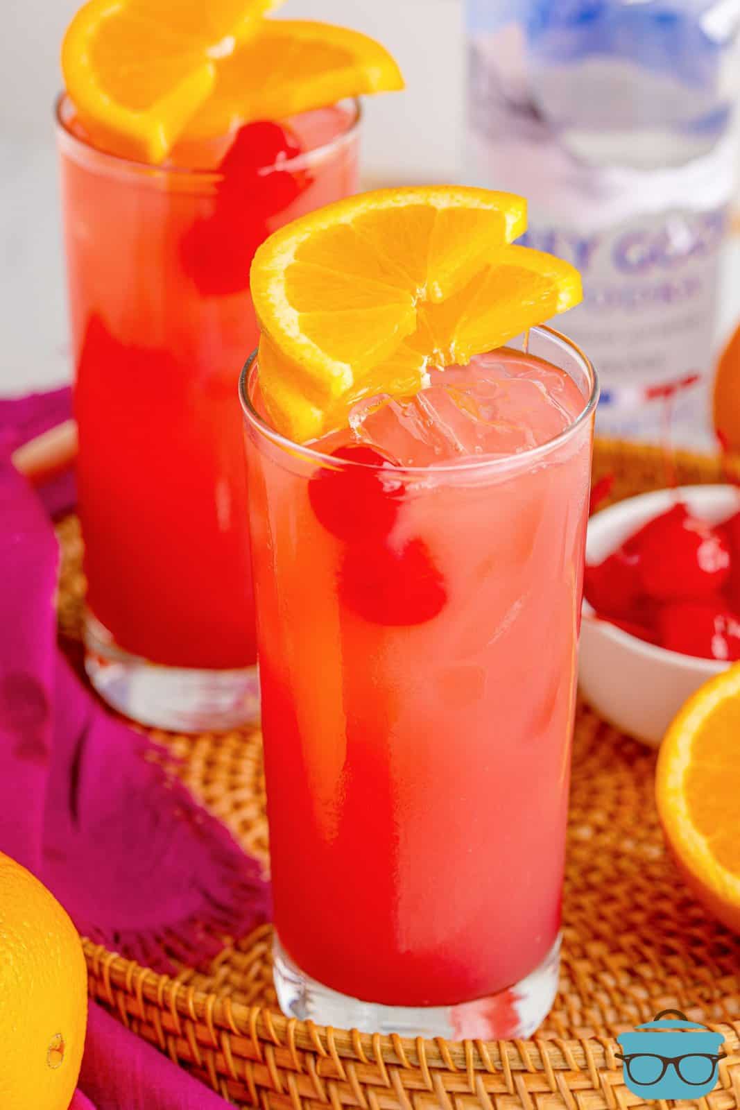 Two glasses of Sex on the Beach with cherry and orange garnishes.