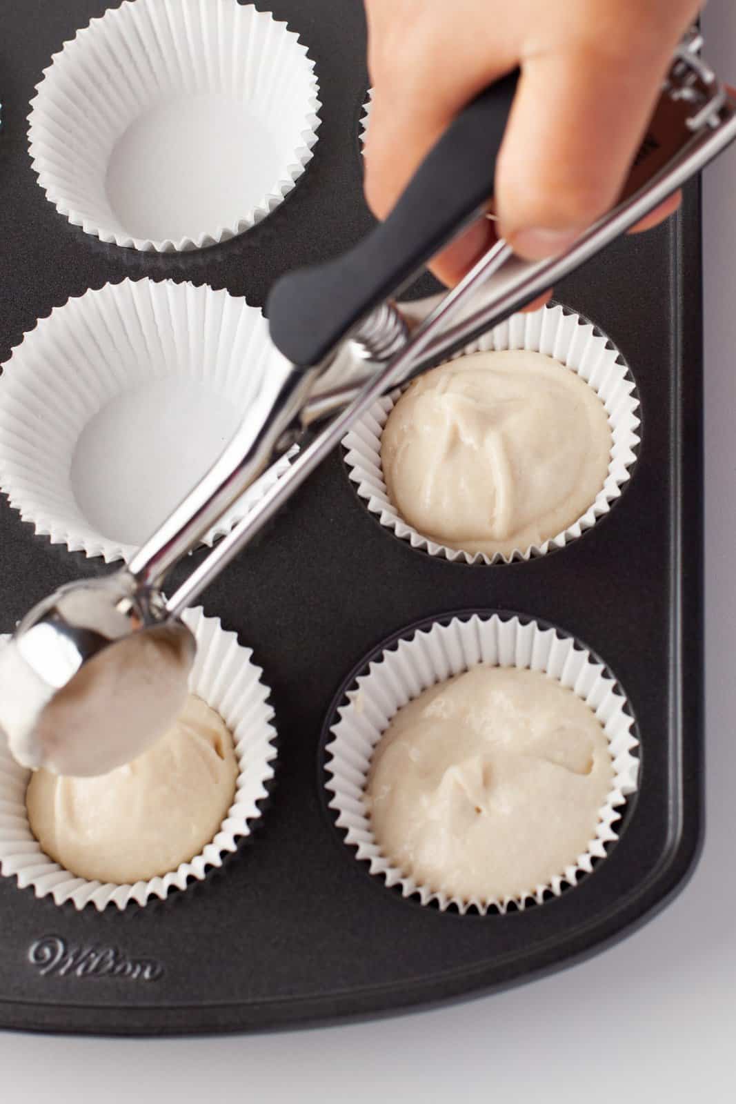 Cupcake batter being placed in liners in pan.