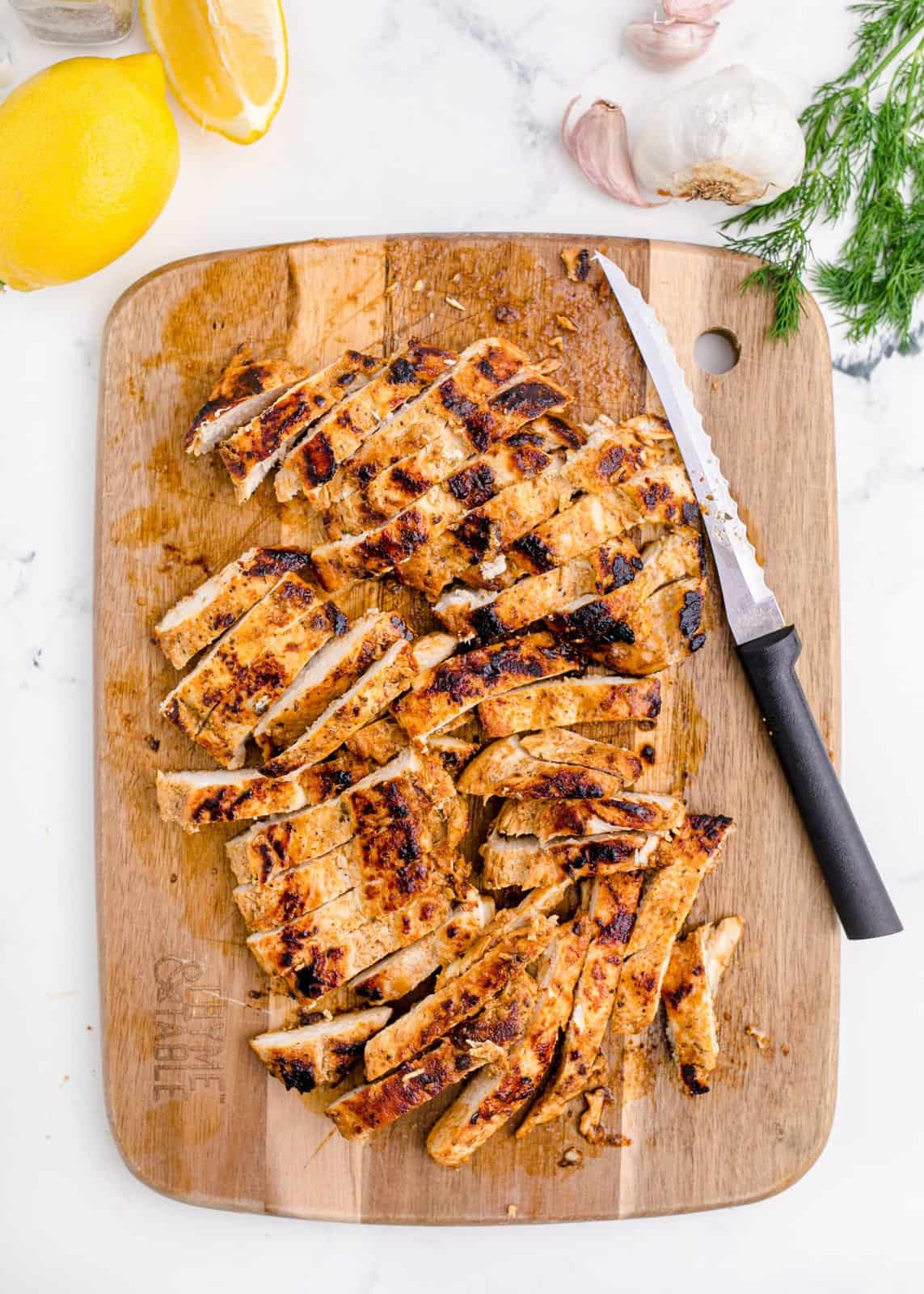 Cut up cooked chicken on cutting board.