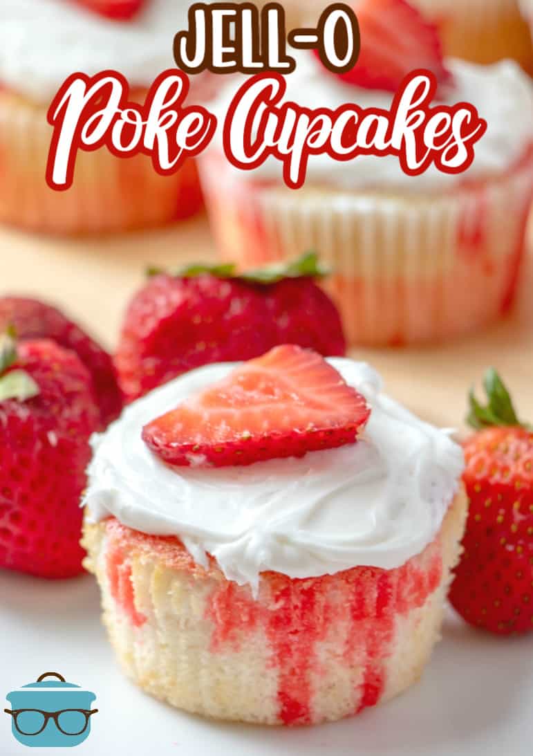 Strawberry Jell-o Poke Cupcakes topped with whipped frosting and a fresh strawberry on a white plate.
