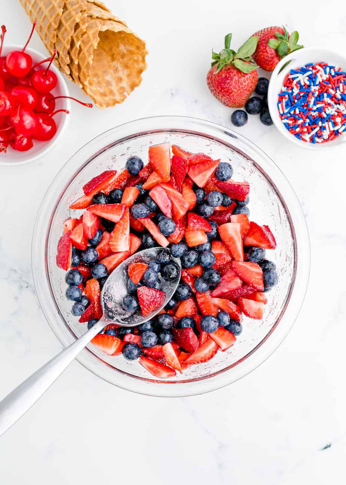 Berries mixed with sugar in bowl.