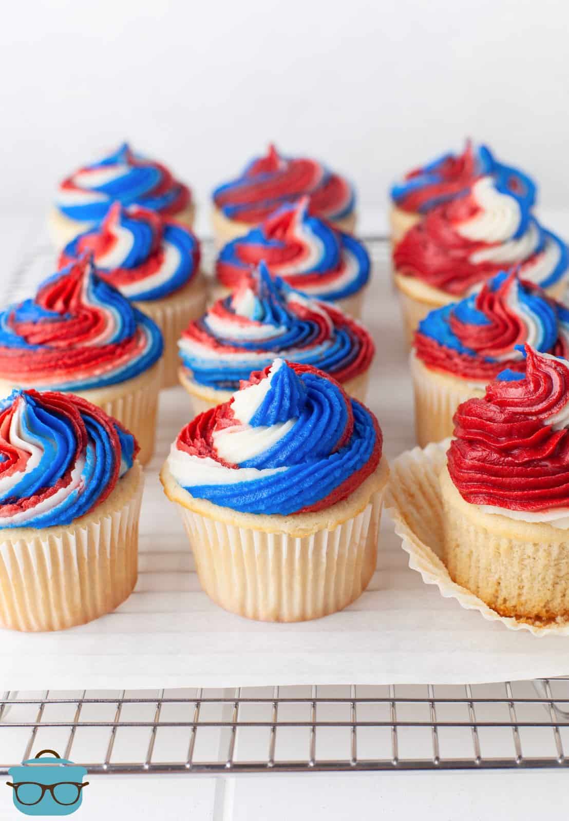 Finished 4th of July Cupcakes on parchment paper on wire rack lined up in rows.