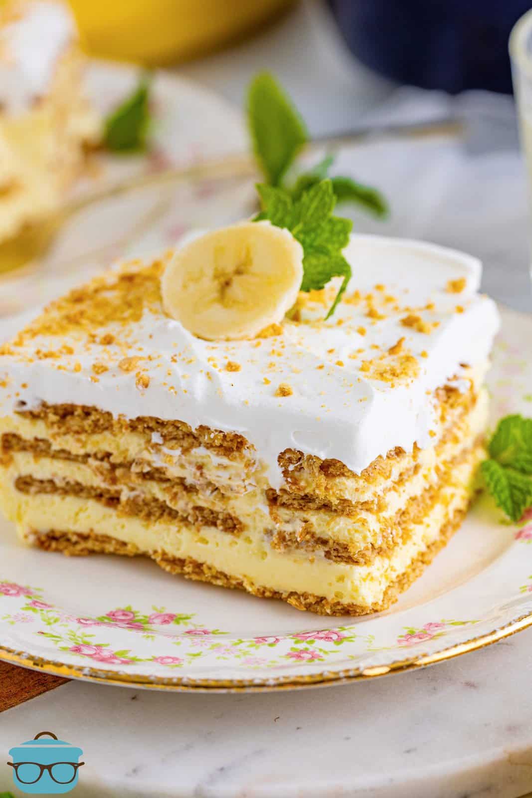 Banana Icebox Cake slice on white plate topped with banana and mint.