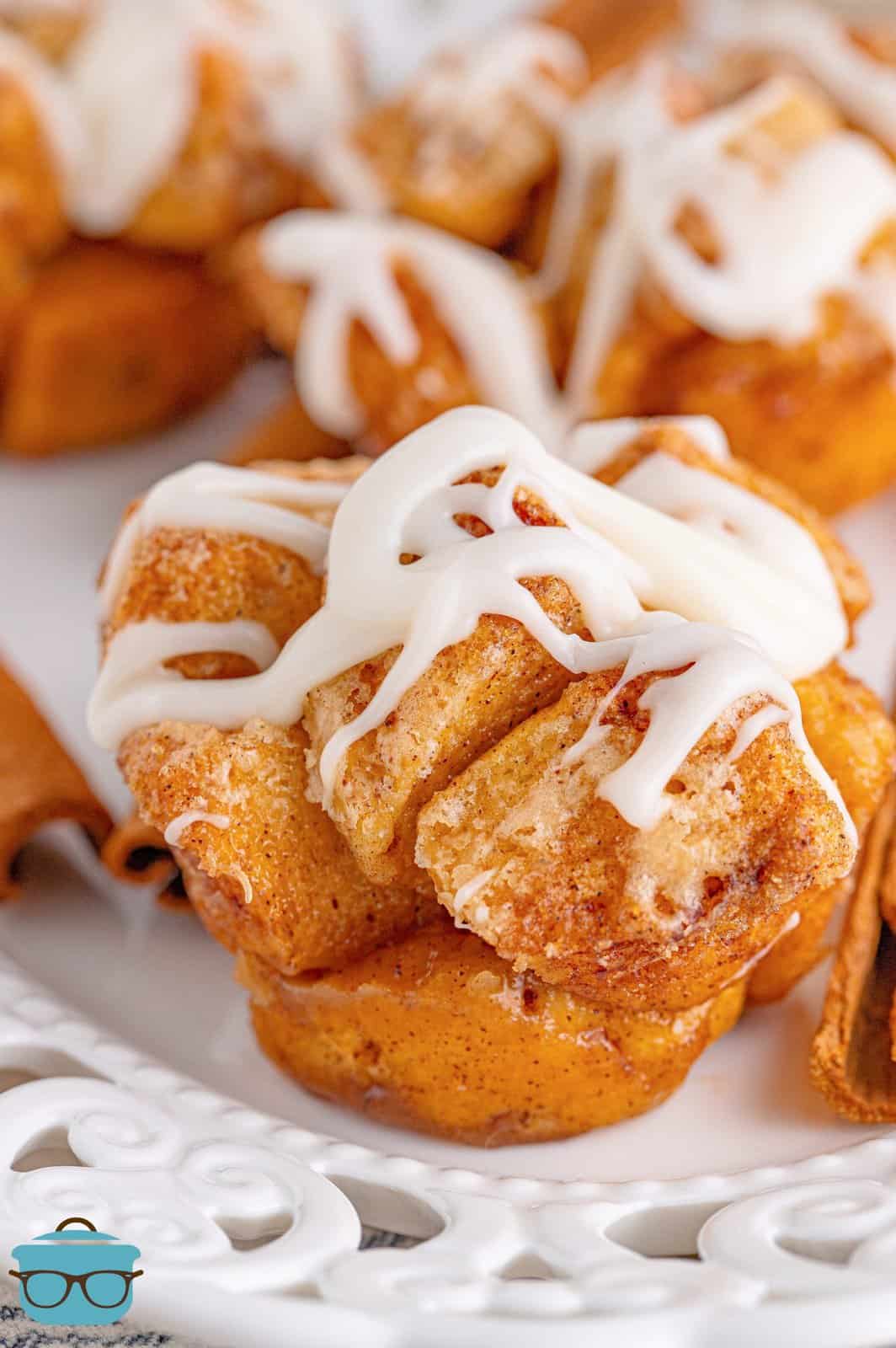 Close up of Cinnamon Roll Monkey Bread Muffins on white tray with glaze on top.